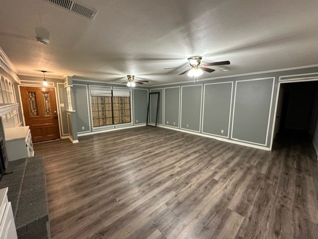 unfurnished living room featuring a textured ceiling, ornamental molding, and dark wood-type flooring