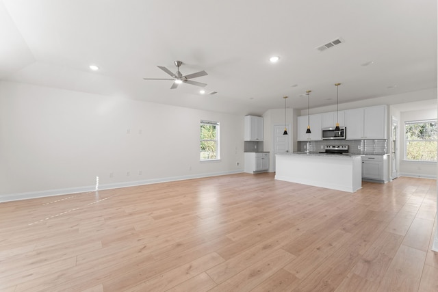 unfurnished living room with ceiling fan, a healthy amount of sunlight, and light hardwood / wood-style flooring