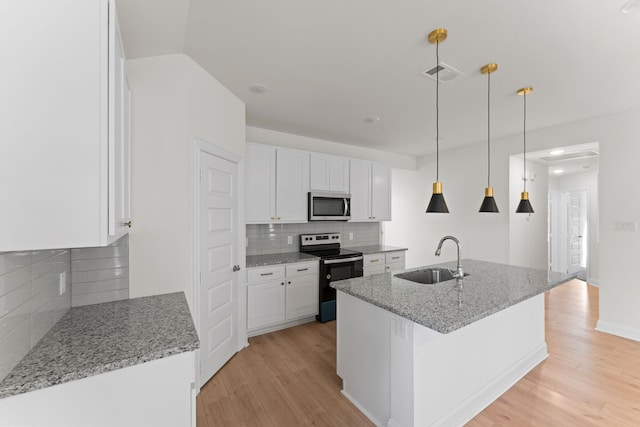 kitchen featuring an island with sink, stainless steel appliances, sink, white cabinets, and light stone counters