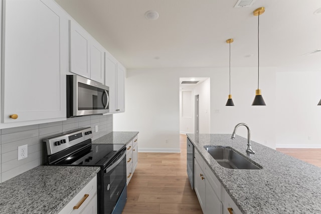 kitchen with white cabinets, light stone counters, stainless steel appliances, and light wood-type flooring