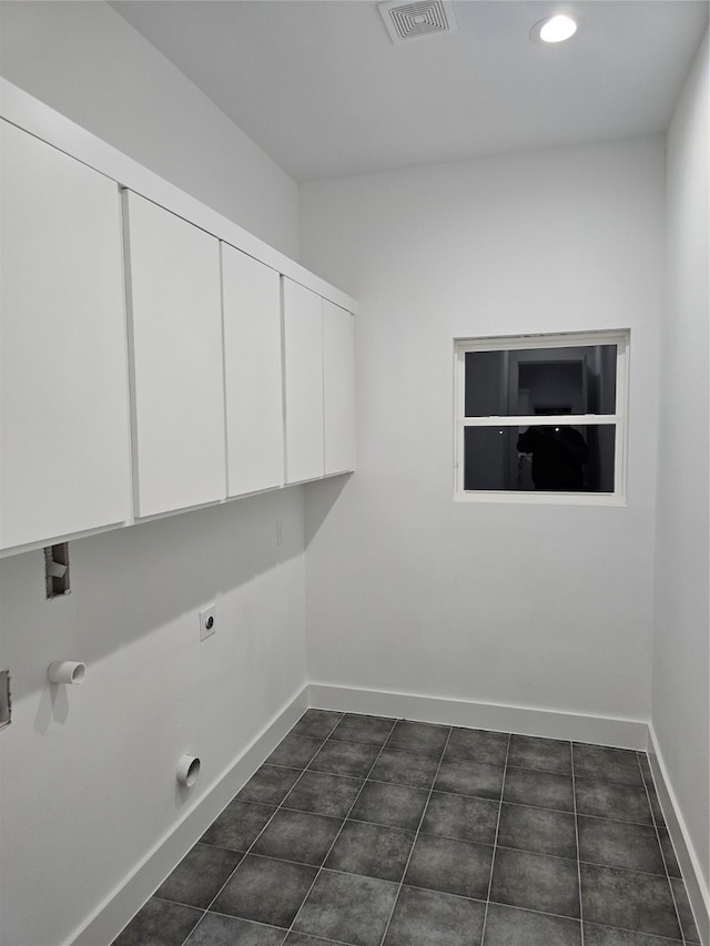 laundry room with hookup for a washing machine, hookup for an electric dryer, gas dryer hookup, dark tile patterned floors, and cabinets