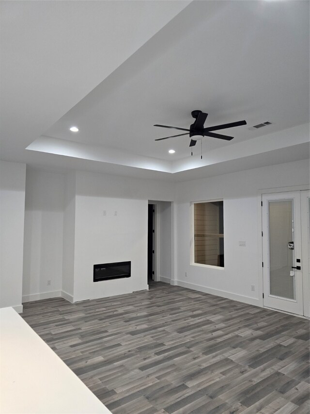 unfurnished living room featuring ceiling fan, hardwood / wood-style flooring, and a raised ceiling