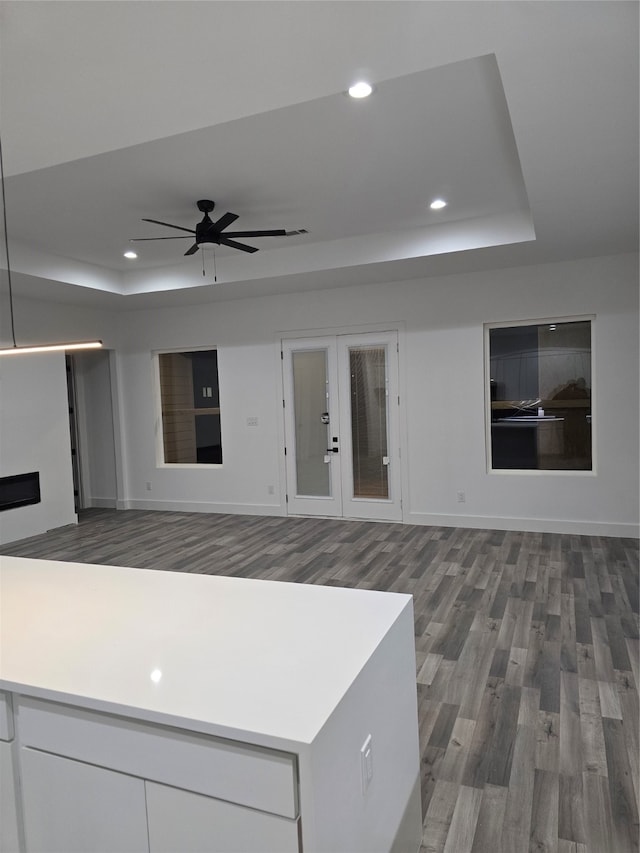 kitchen with ceiling fan, white cabinetry, hardwood / wood-style flooring, a tray ceiling, and french doors