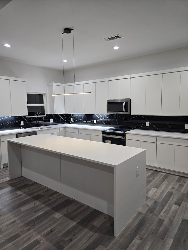 kitchen with dark hardwood / wood-style floors, sink, black electric range, decorative light fixtures, and a center island