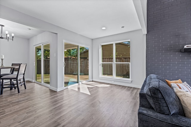 living room with hardwood / wood-style flooring, a chandelier, and brick wall