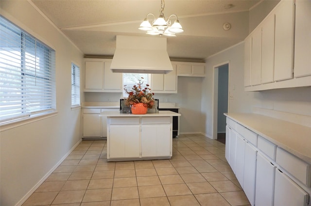 kitchen featuring custom exhaust hood, a kitchen island, white cabinetry, light tile patterned flooring, and pendant lighting