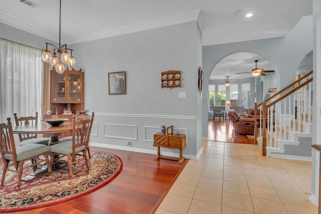 dining space featuring light hardwood / wood-style floors, ornamental molding, and ceiling fan with notable chandelier