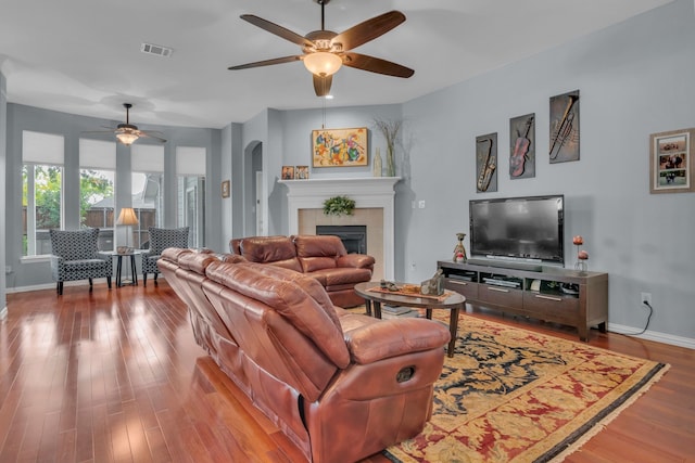 living room featuring ceiling fan, hardwood / wood-style flooring, and a tile fireplace