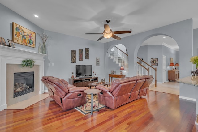 living room with ceiling fan, crown molding, light hardwood / wood-style flooring, and a fireplace