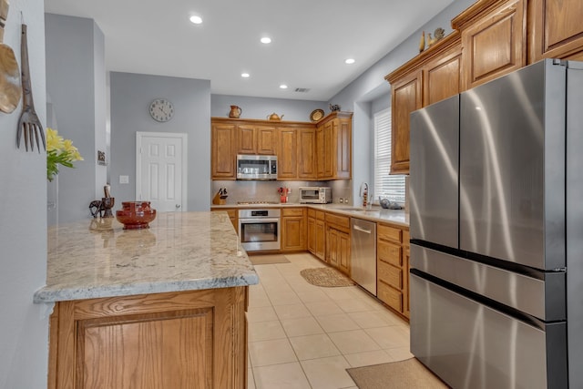 kitchen featuring kitchen peninsula, stainless steel appliances, sink, light stone countertops, and light tile patterned flooring