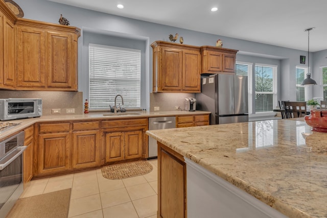 kitchen featuring appliances with stainless steel finishes, decorative light fixtures, sink, and light tile patterned floors