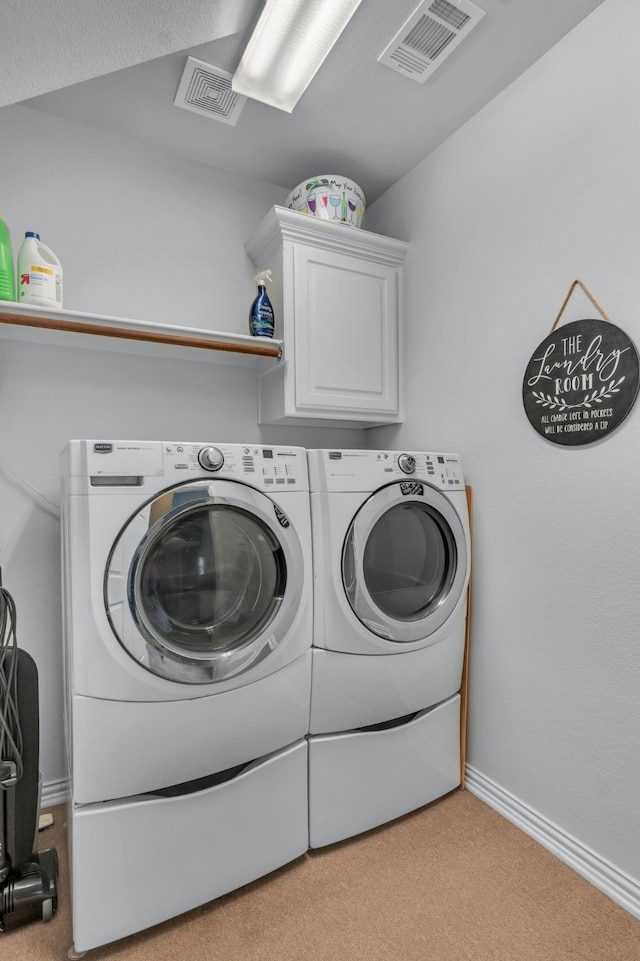 laundry area with cabinets, washer and dryer, and light carpet