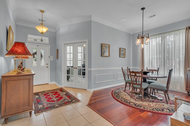 foyer featuring ornamental molding, french doors, light tile patterned flooring, and a notable chandelier