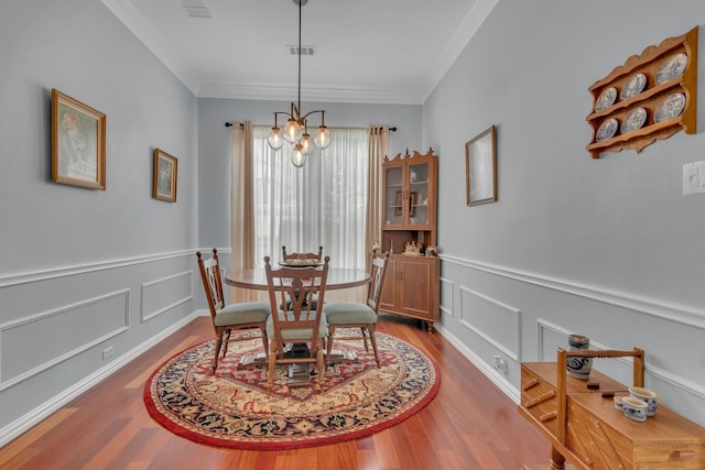 dining area featuring crown molding, hardwood / wood-style flooring, and an inviting chandelier