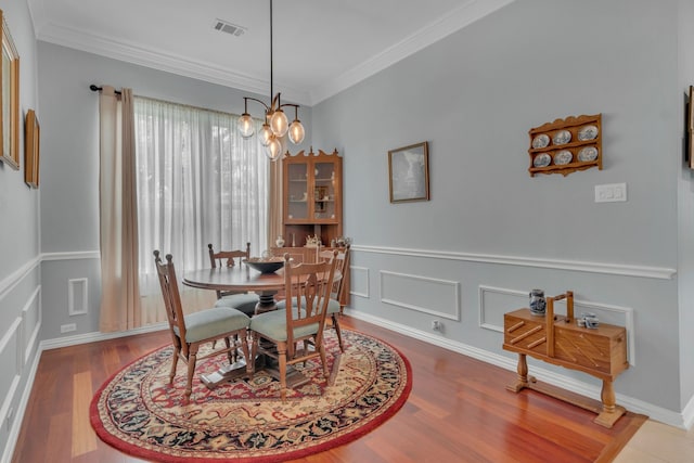 dining room featuring crown molding, an inviting chandelier, and hardwood / wood-style floors