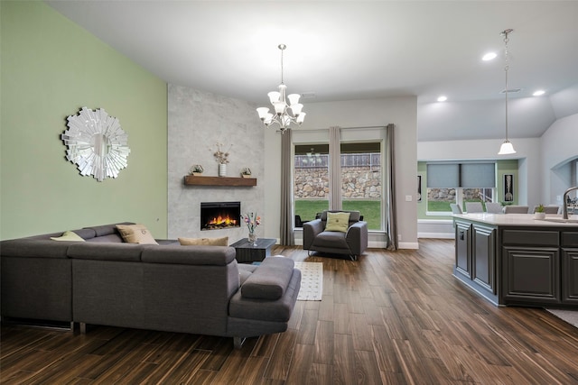 living room with lofted ceiling, sink, an inviting chandelier, a fireplace, and dark hardwood / wood-style flooring