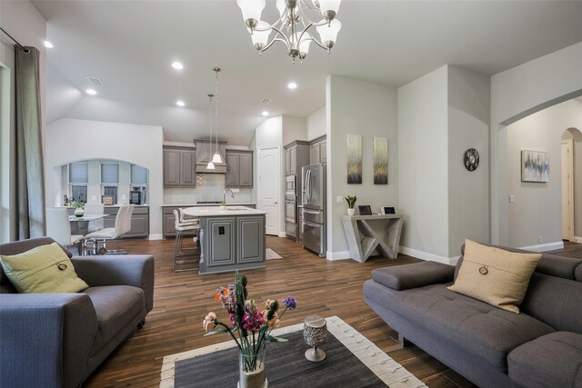 living room with lofted ceiling, dark hardwood / wood-style floors, a chandelier, and sink