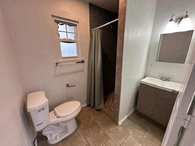 bathroom featuring toilet, a shower with curtain, vanity, and tile patterned floors