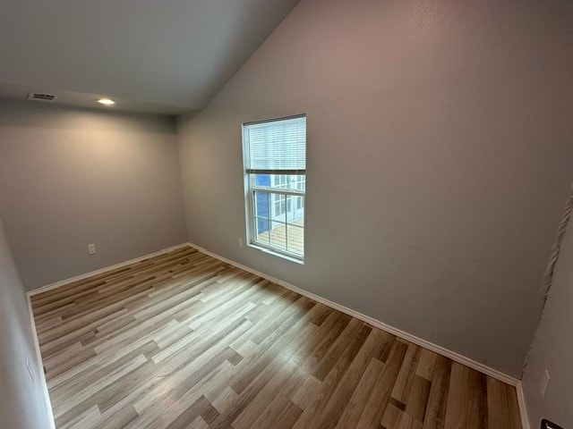 spare room featuring light hardwood / wood-style floors and lofted ceiling