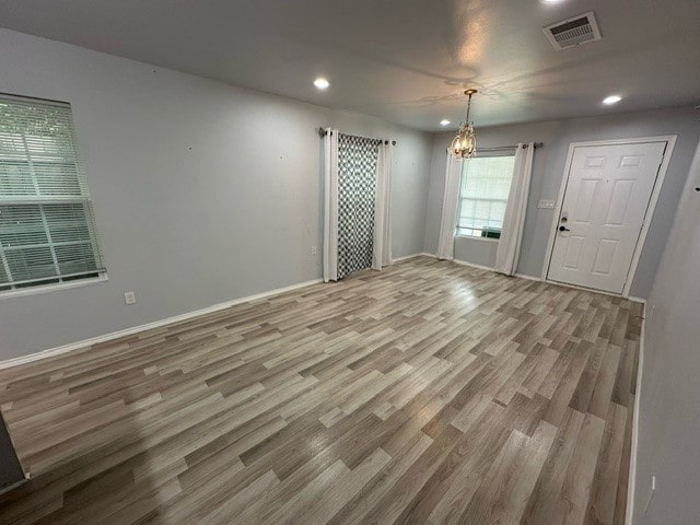 unfurnished room featuring hardwood / wood-style flooring and an inviting chandelier