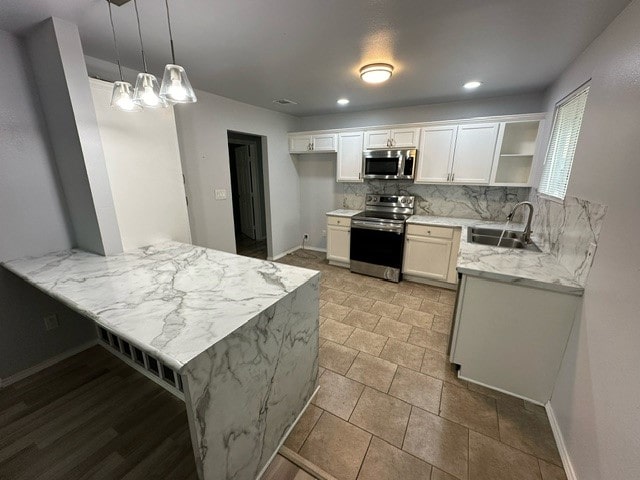 kitchen with backsplash, kitchen peninsula, stainless steel appliances, pendant lighting, and white cabinets