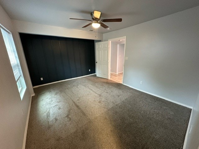 unfurnished bedroom featuring ceiling fan, carpet, and multiple windows