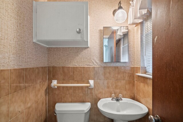 bathroom with toilet, tile walls, and sink