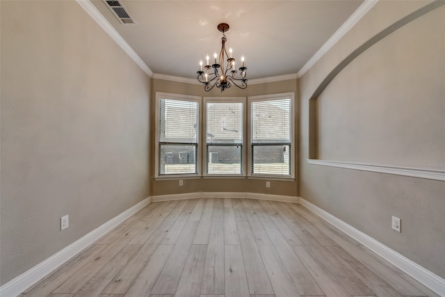 spare room featuring light hardwood / wood-style floors, an inviting chandelier, and crown molding