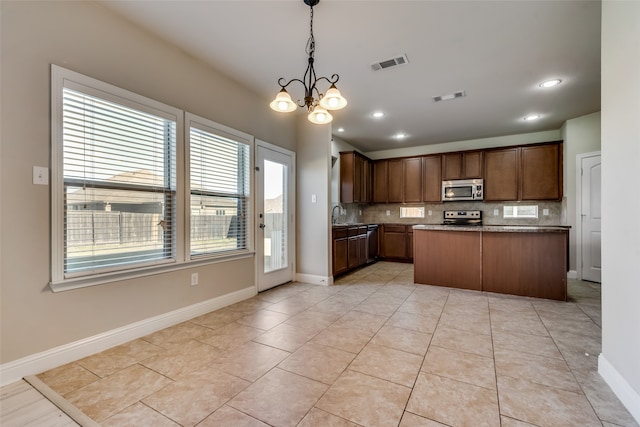 kitchen featuring a kitchen island, backsplash, an inviting chandelier, stainless steel appliances, and decorative light fixtures