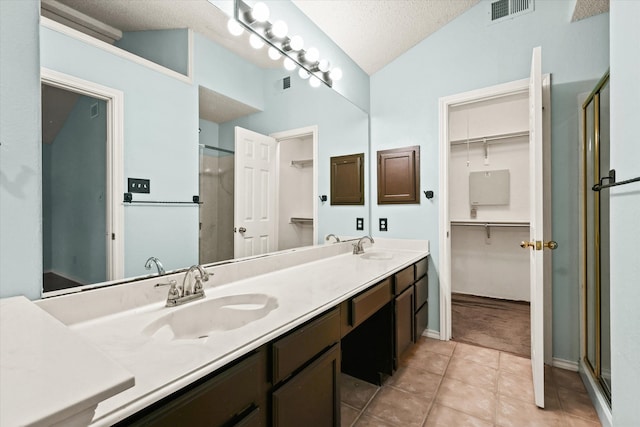 bathroom with vaulted ceiling, a shower with shower door, a textured ceiling, and tile patterned flooring