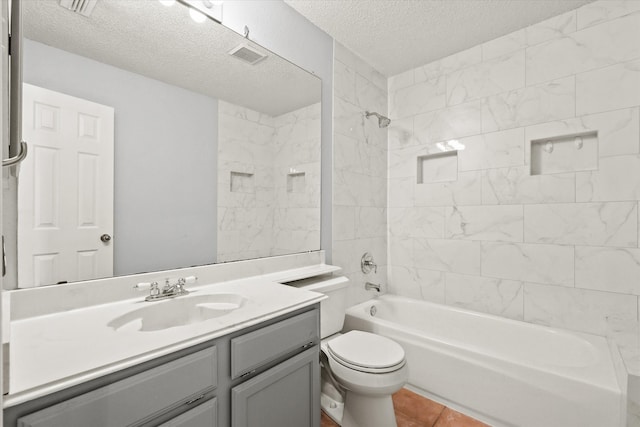 full bathroom with tiled shower / bath, a textured ceiling, toilet, vanity, and tile patterned floors