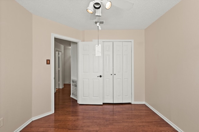 unfurnished bedroom with a closet, ceiling fan, a textured ceiling, and dark hardwood / wood-style floors