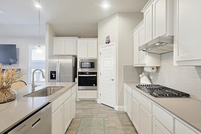 kitchen featuring sink, decorative light fixtures, light hardwood / wood-style floors, white cabinetry, and stainless steel appliances