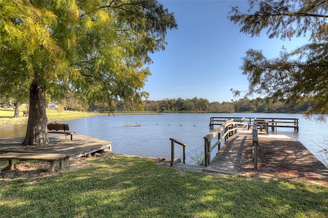 view of dock with a water view and a lawn