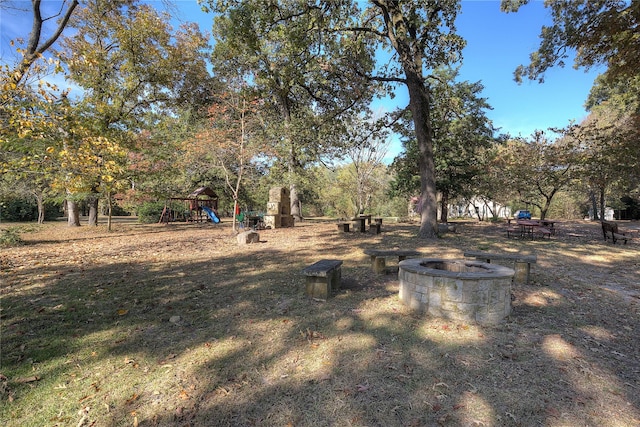 view of yard featuring a playground and an outdoor fire pit