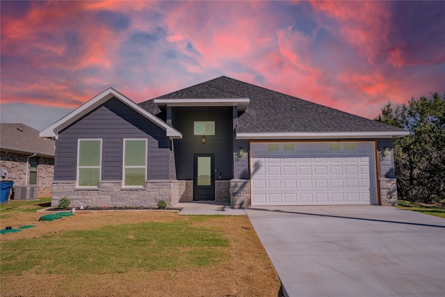 view of front facade with central AC unit, a garage, and a lawn