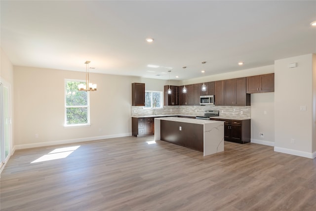 kitchen featuring light wood-type flooring, a kitchen island, pendant lighting, and appliances with stainless steel finishes