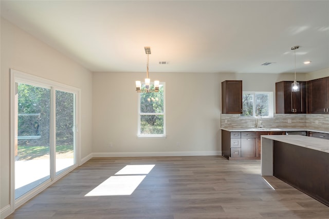 kitchen with light wood-type flooring, decorative backsplash, and decorative light fixtures