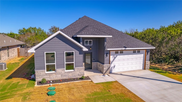 view of front of property with central air condition unit, a garage, and a front lawn