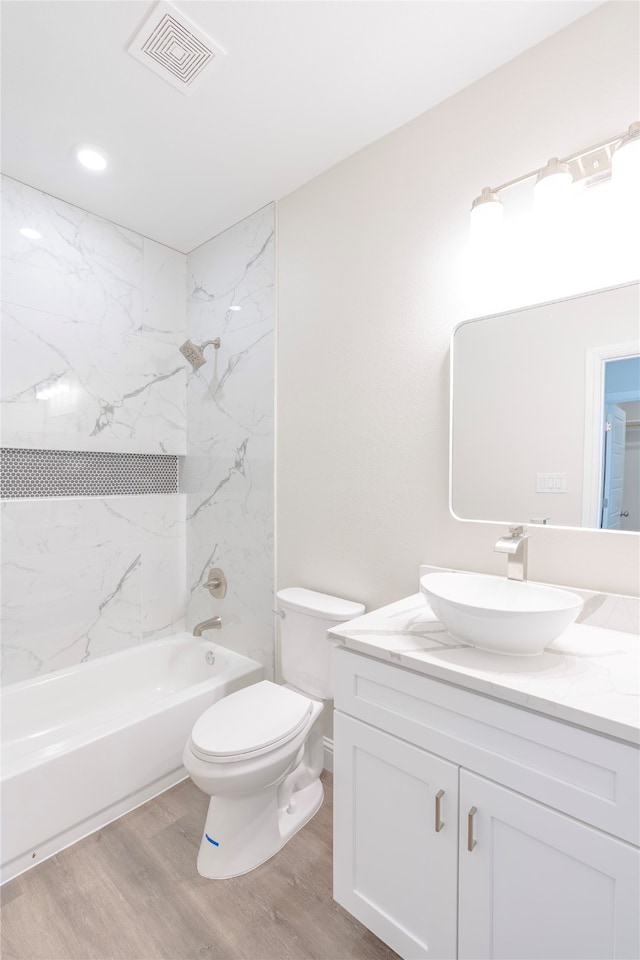 full bathroom with wood-type flooring, vanity, toilet, and tiled shower / bath combo