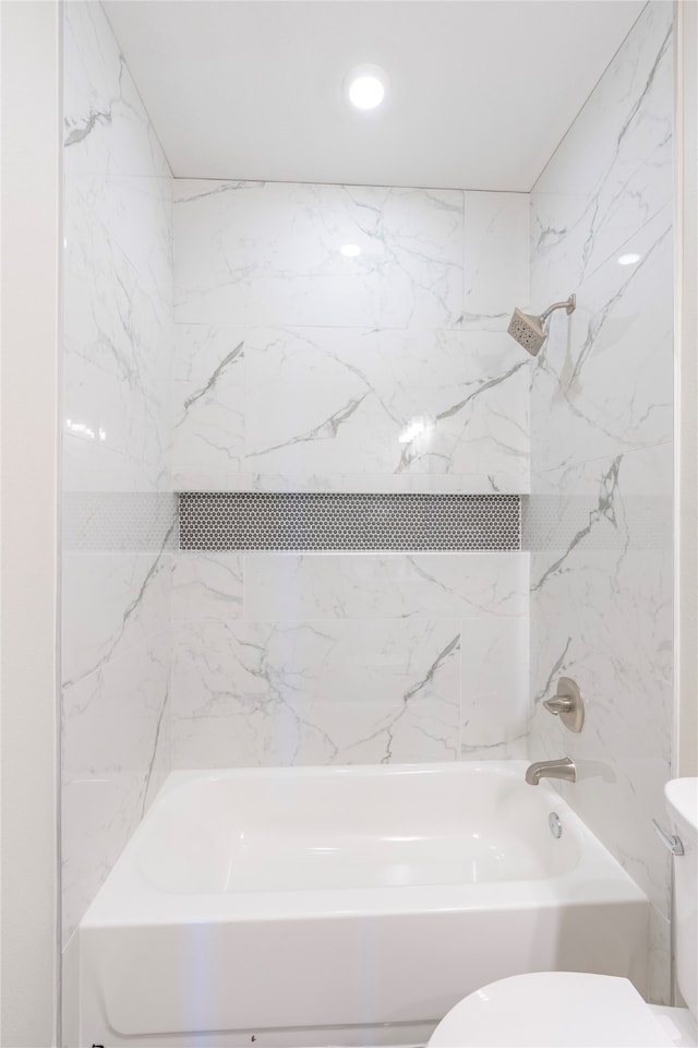 bathroom with toilet and tiled shower / bath combo