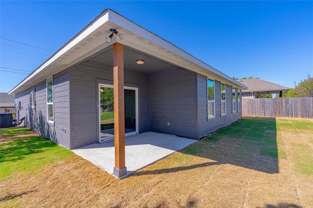 rear view of house with a yard, a patio, and central AC