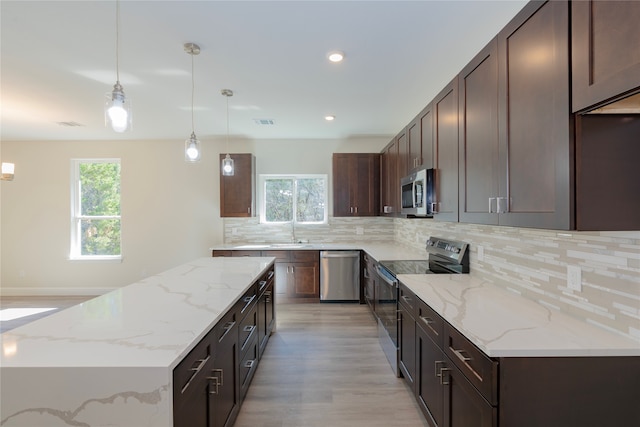 kitchen featuring a wealth of natural light, pendant lighting, appliances with stainless steel finishes, and light hardwood / wood-style floors