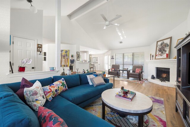 living room with hardwood / wood-style floors, high vaulted ceiling, a brick fireplace, ceiling fan, and beam ceiling