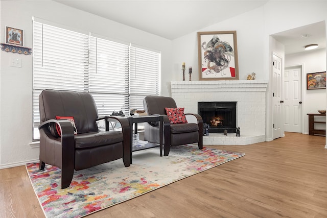 living area featuring plenty of natural light, light hardwood / wood-style floors, a fireplace, and vaulted ceiling