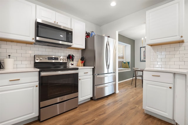 kitchen featuring appliances with stainless steel finishes, light wood-type flooring, tasteful backsplash, and white cabinetry