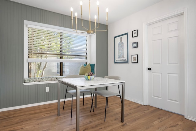 dining space featuring wood walls, wood-type flooring, and an inviting chandelier