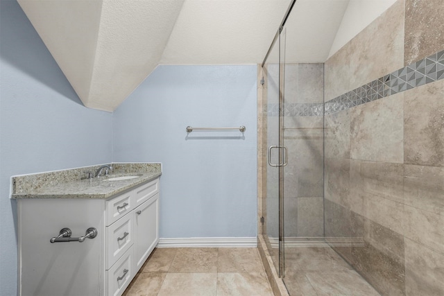 bathroom featuring a textured ceiling, a shower with door, vanity, and lofted ceiling