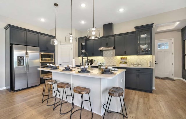 kitchen featuring a center island with sink, decorative light fixtures, and appliances with stainless steel finishes