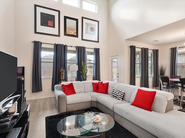 living room featuring a healthy amount of sunlight, light hardwood / wood-style floors, and a high ceiling